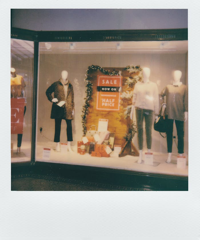 Chic boutique window showcasing women's fashion with a prominent sale sign.