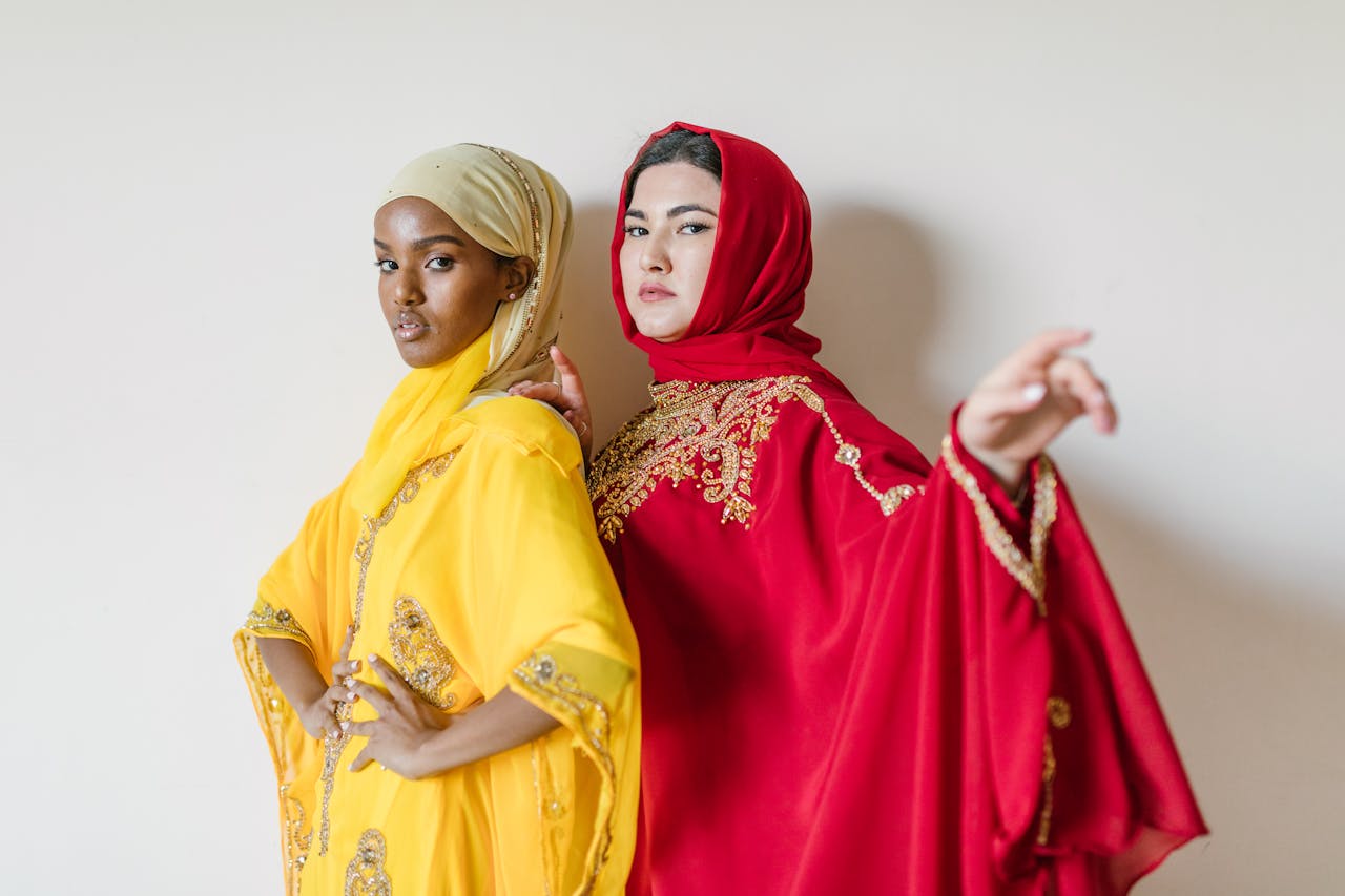 Two women in vibrant yellow and red hijabs showcasing elegant Muslim fashion and modest clothing.